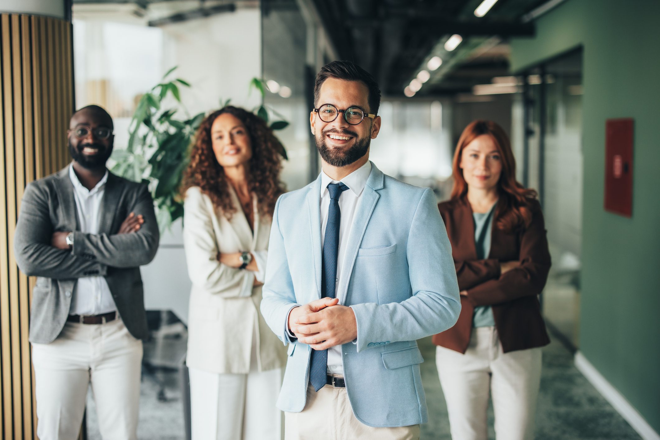 Group of professionals standing in office hallway.