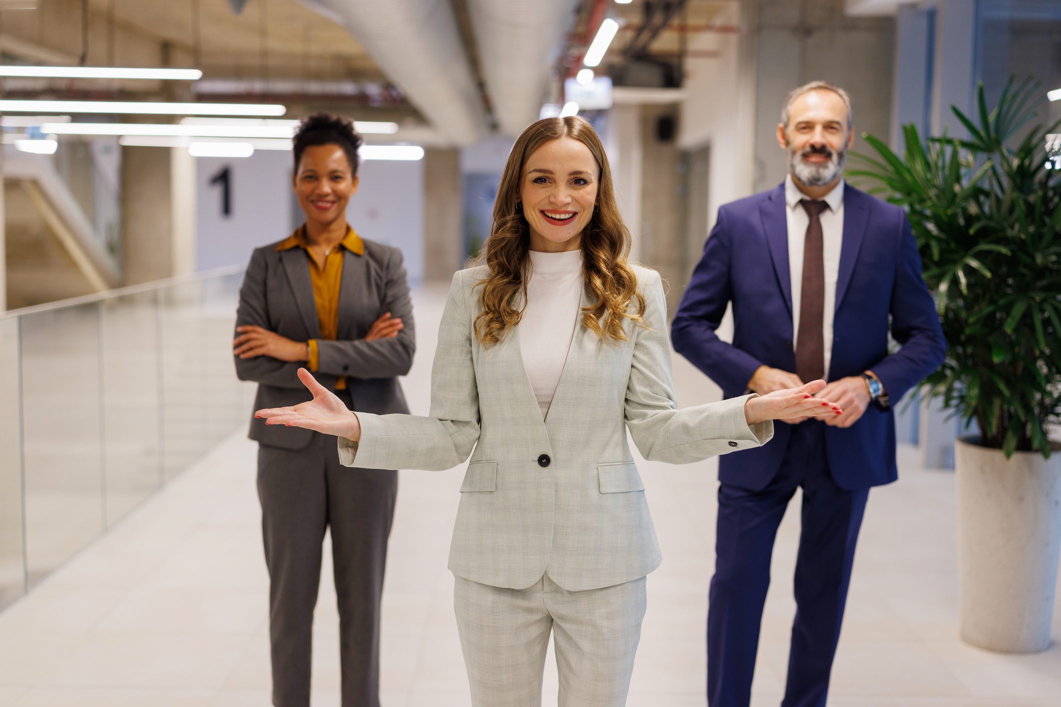 Business team posing in modern office hallway.