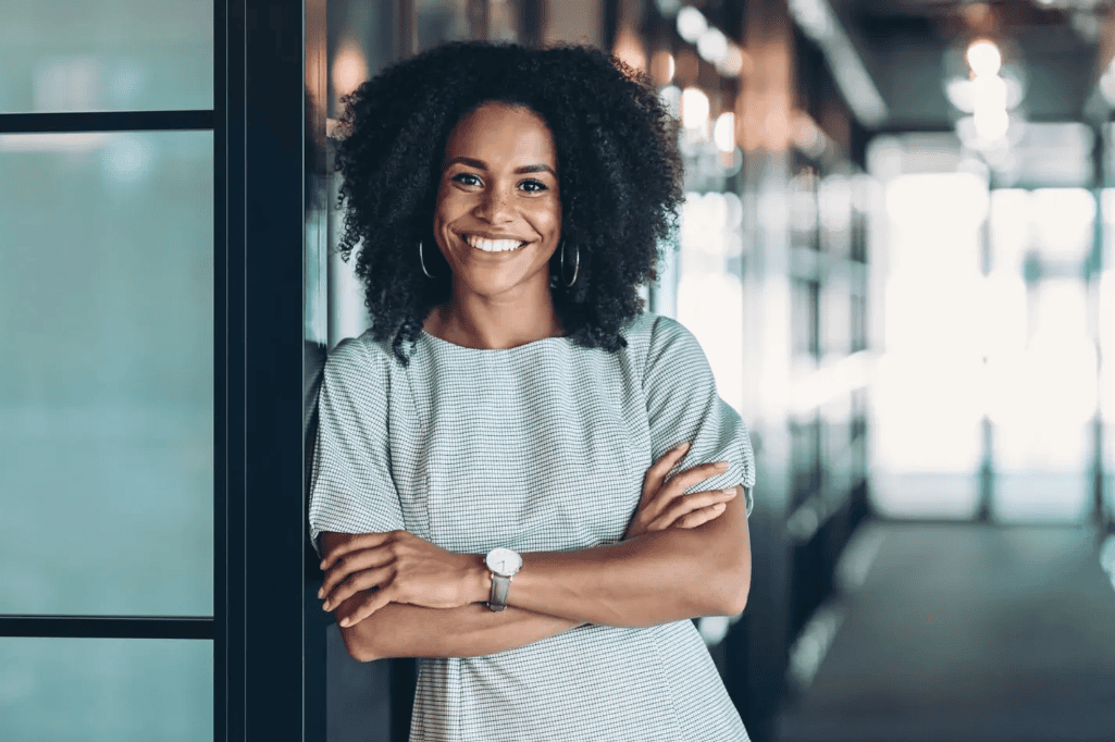 Smiling woman with arms crossed in office