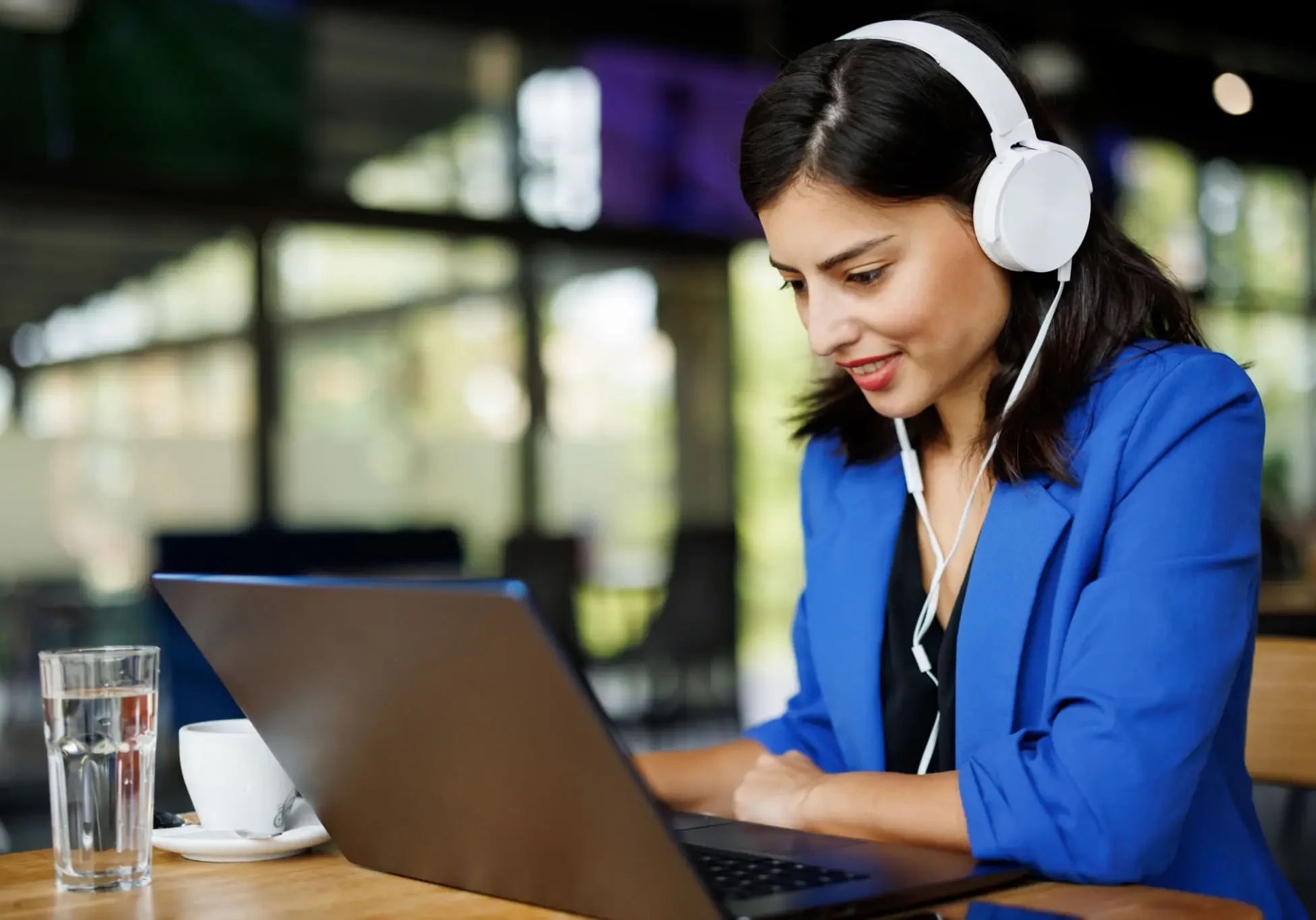 Woman with headphones using laptop in cafe.