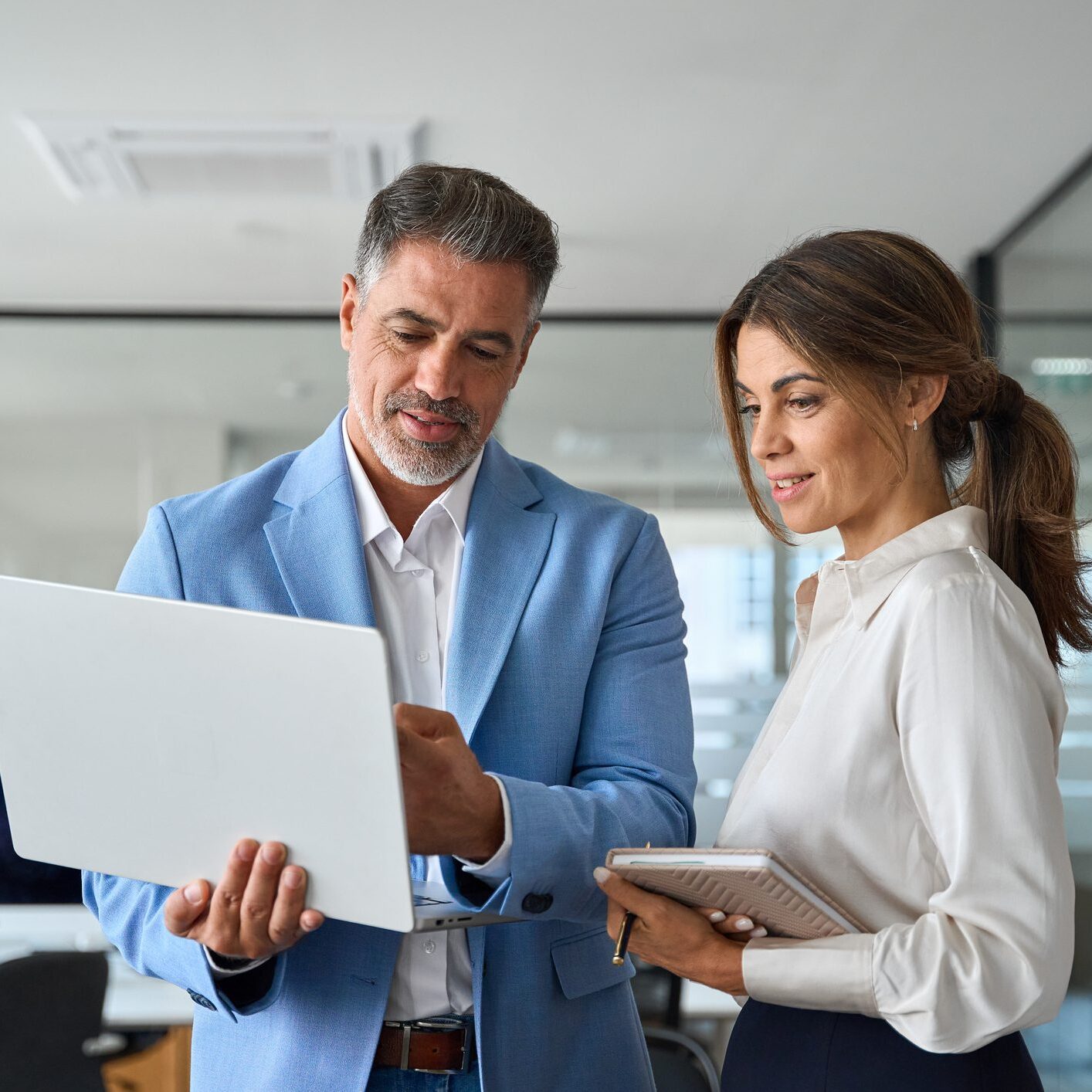 Two professionals discussing work on laptop.