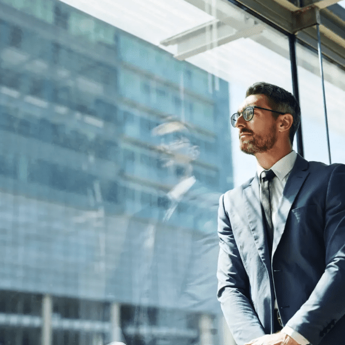 Businessman in suit standing by office window.